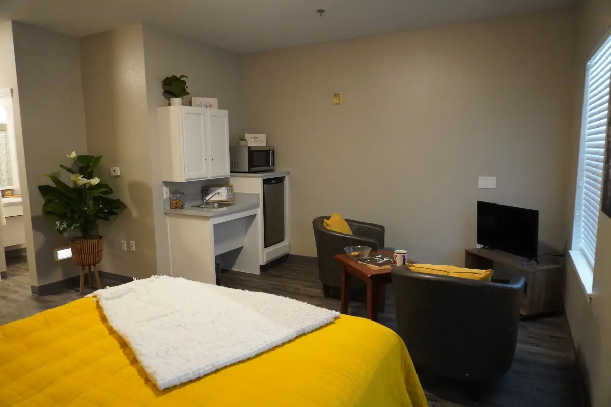 A furnished model apartment with a bed, seating and a window